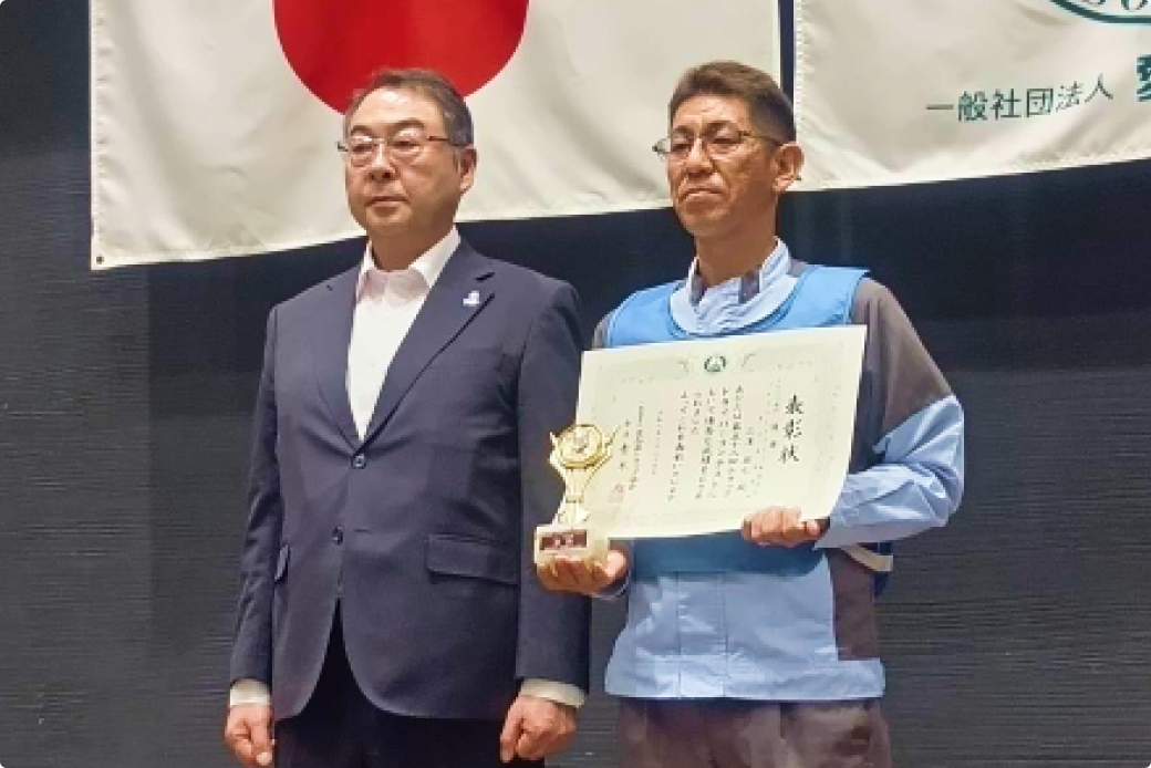 表彰状とトロフィーを手にした当社社員